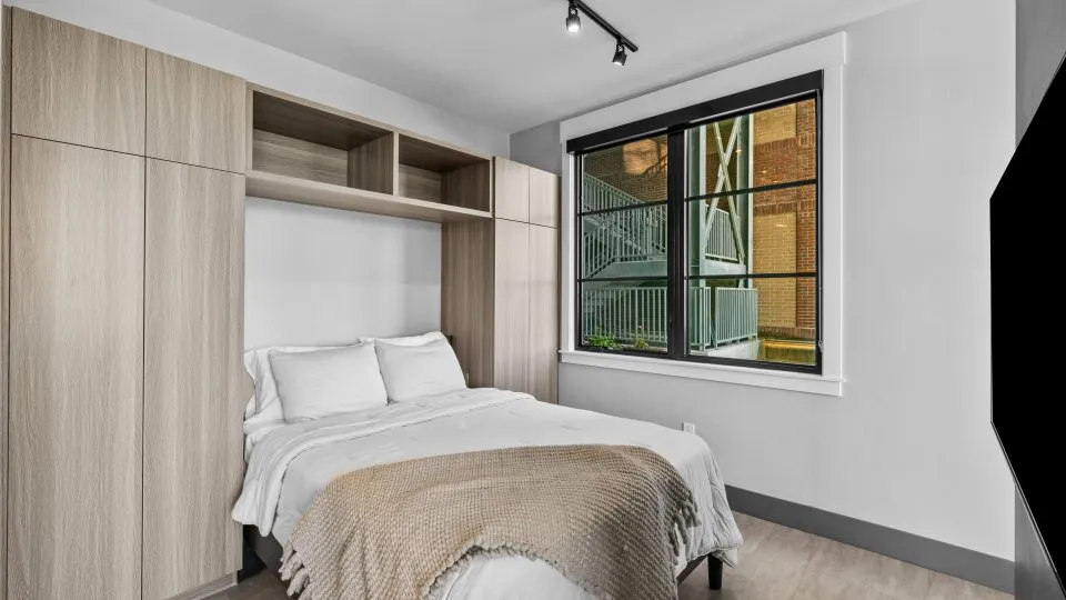 Apartment bedroom at Salt Lake Crossing with built in shelves and large window.