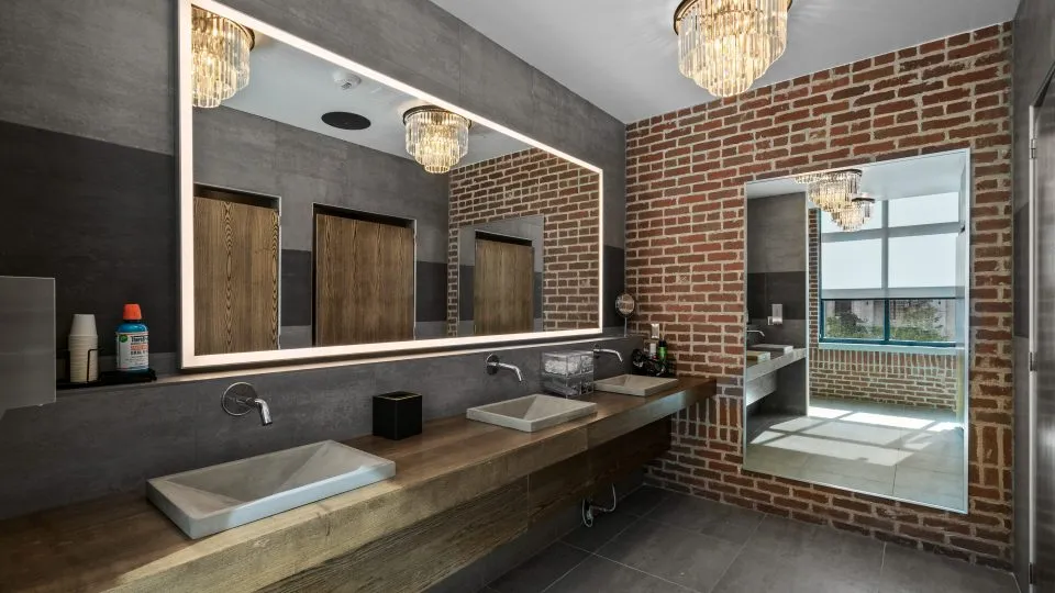Salt Lake Crossing bathroom with large mirror, stone sinks, and chandelier.