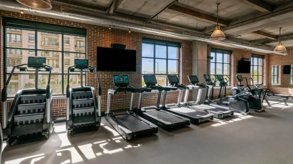Salt Lake Crossing fitness center with cardio machines and large windows.