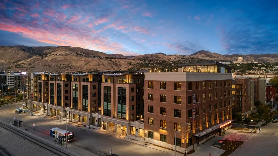 Salt Lake Crossing exterior with brick construction and rooftop deck at dusk.